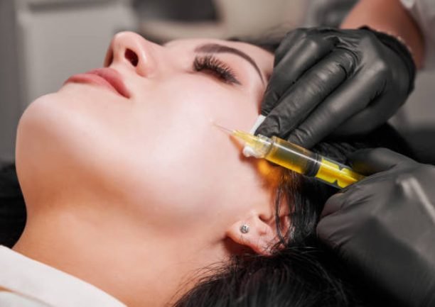 Close-up of plasmolifting procedure injection. Doctor cosmetologist beautician in black sterile gloves making injection in female patient face. Concept of skincare treatment.