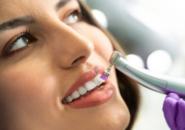 Closeup young woman getting her teeth polished bright background